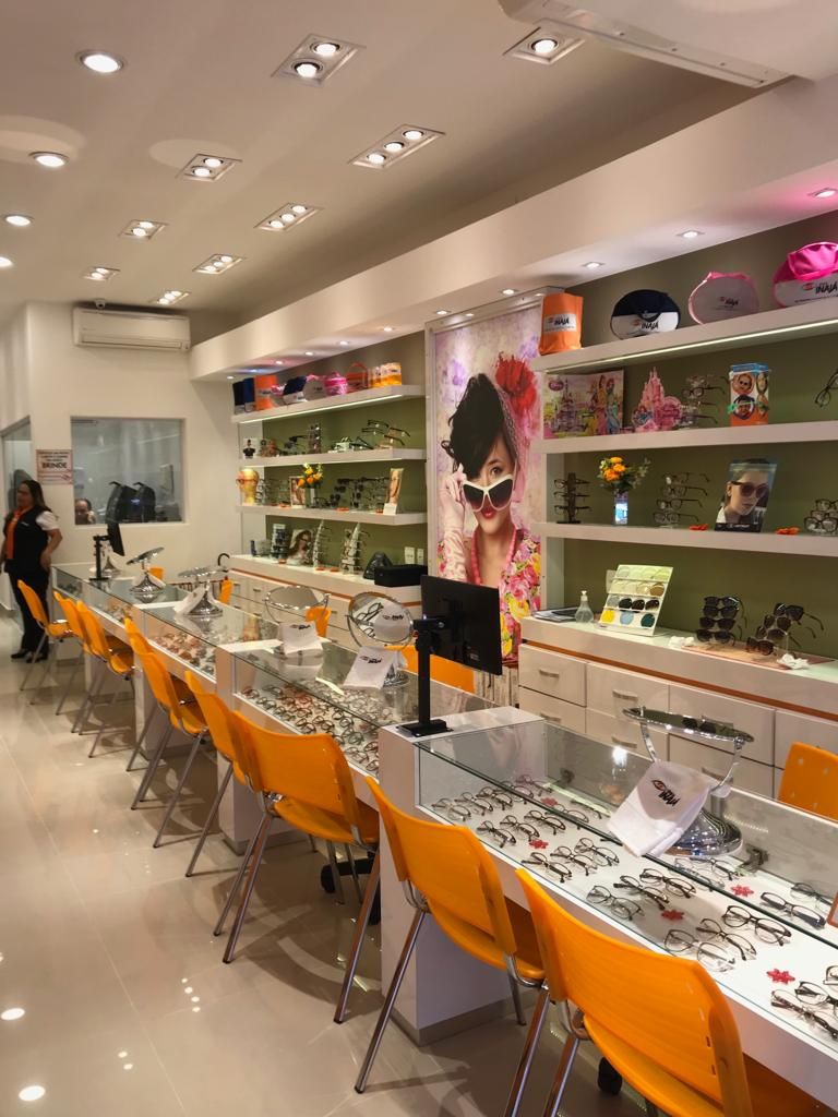 Uma mulher está em uma loja de ótica olhando óculos.