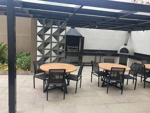 Um pátio com mesas e cadeiras e uma churrasqueira.