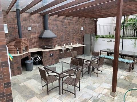 Um pátio com mesas e cadeiras e uma churrasqueira.