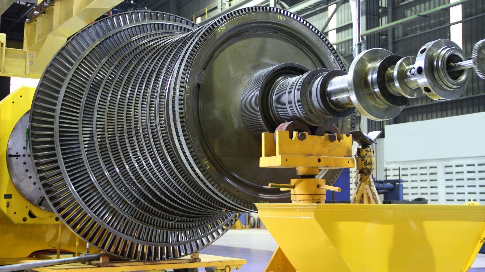 A large turbine is sitting on top of a yellow cart in a factory.