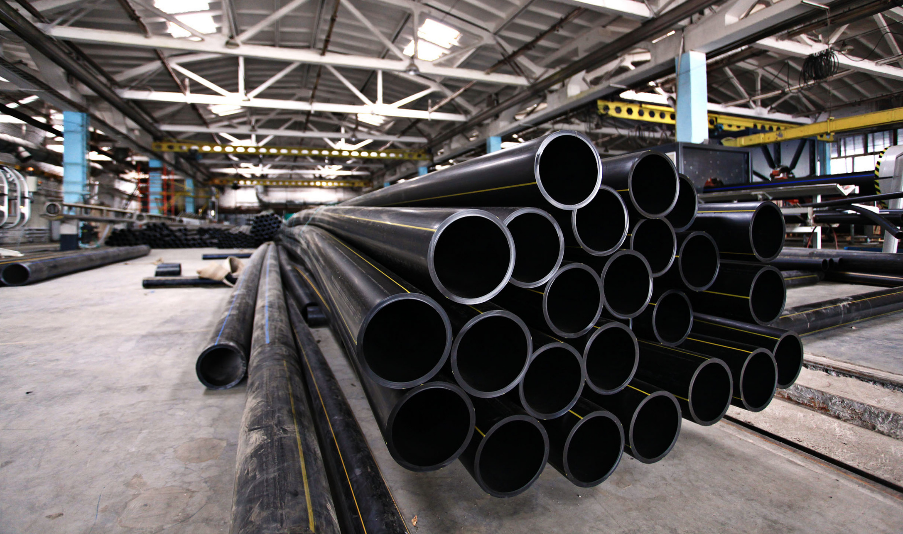 Black pipes stacked in a factory.