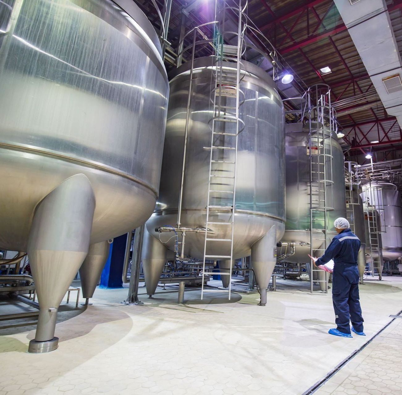 A man stands in front of a row of large metal tanks