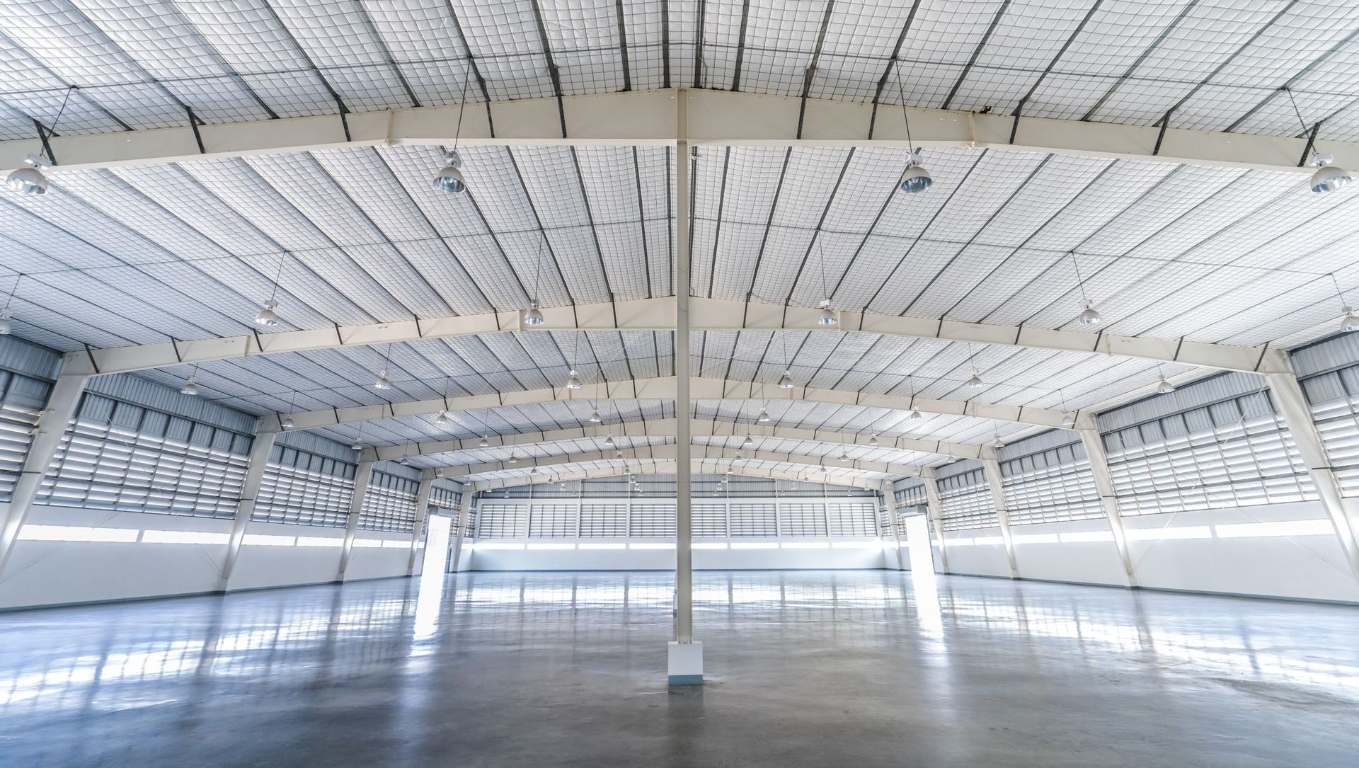 A large empty warehouse with a white ceiling and concrete floor.