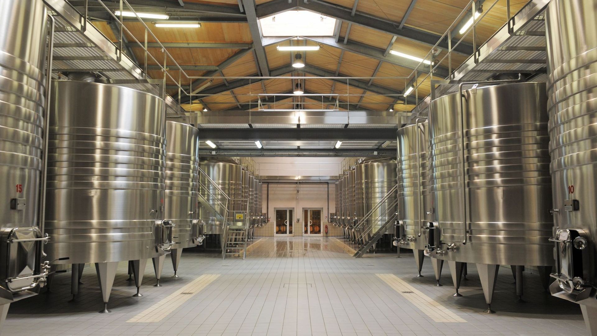 A warehouse filled with lots of stainless steel tanks