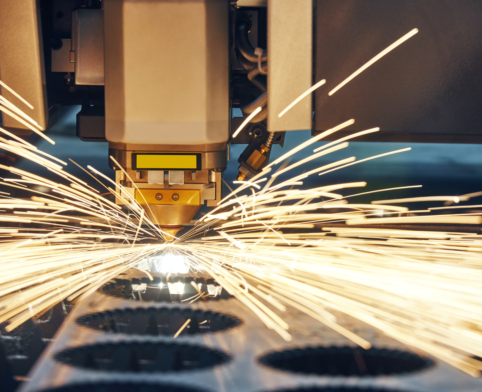 A machine is cutting a piece of metal with sparks coming out of it