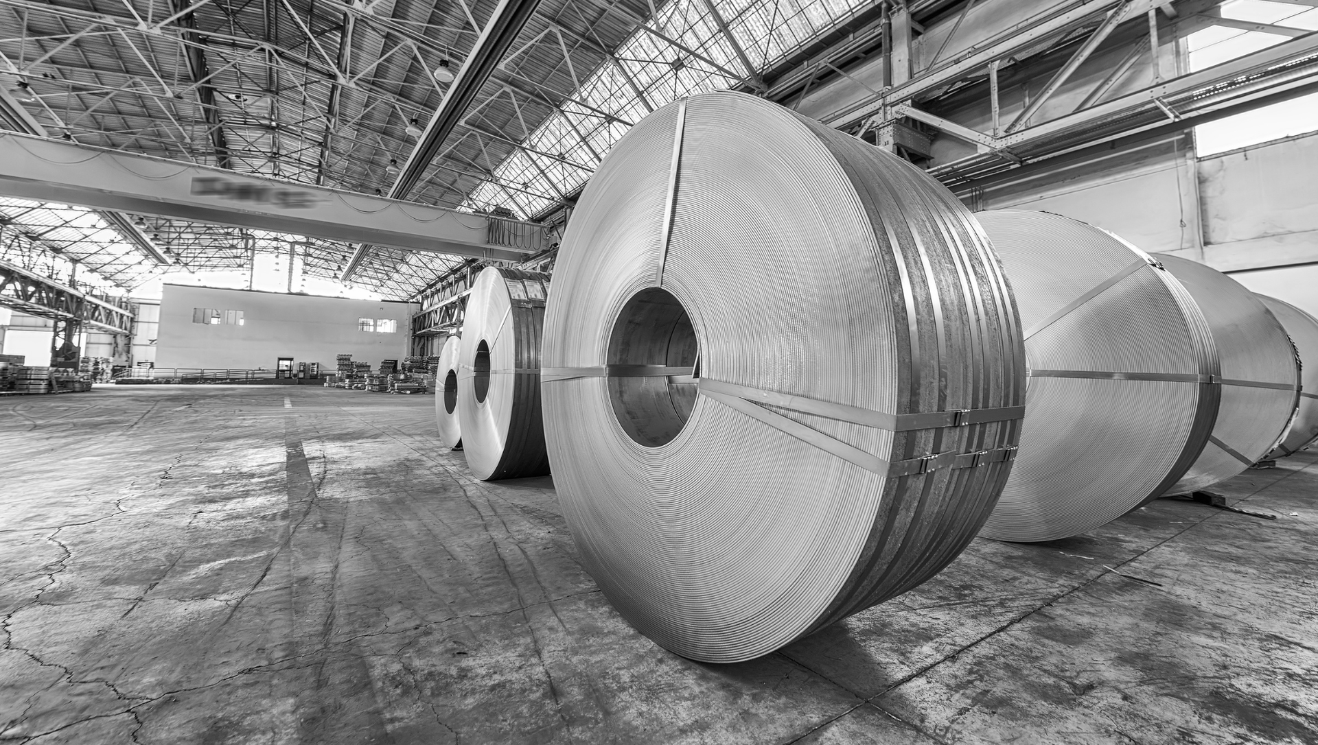 A black and white photo of rolls of steel in a factory.