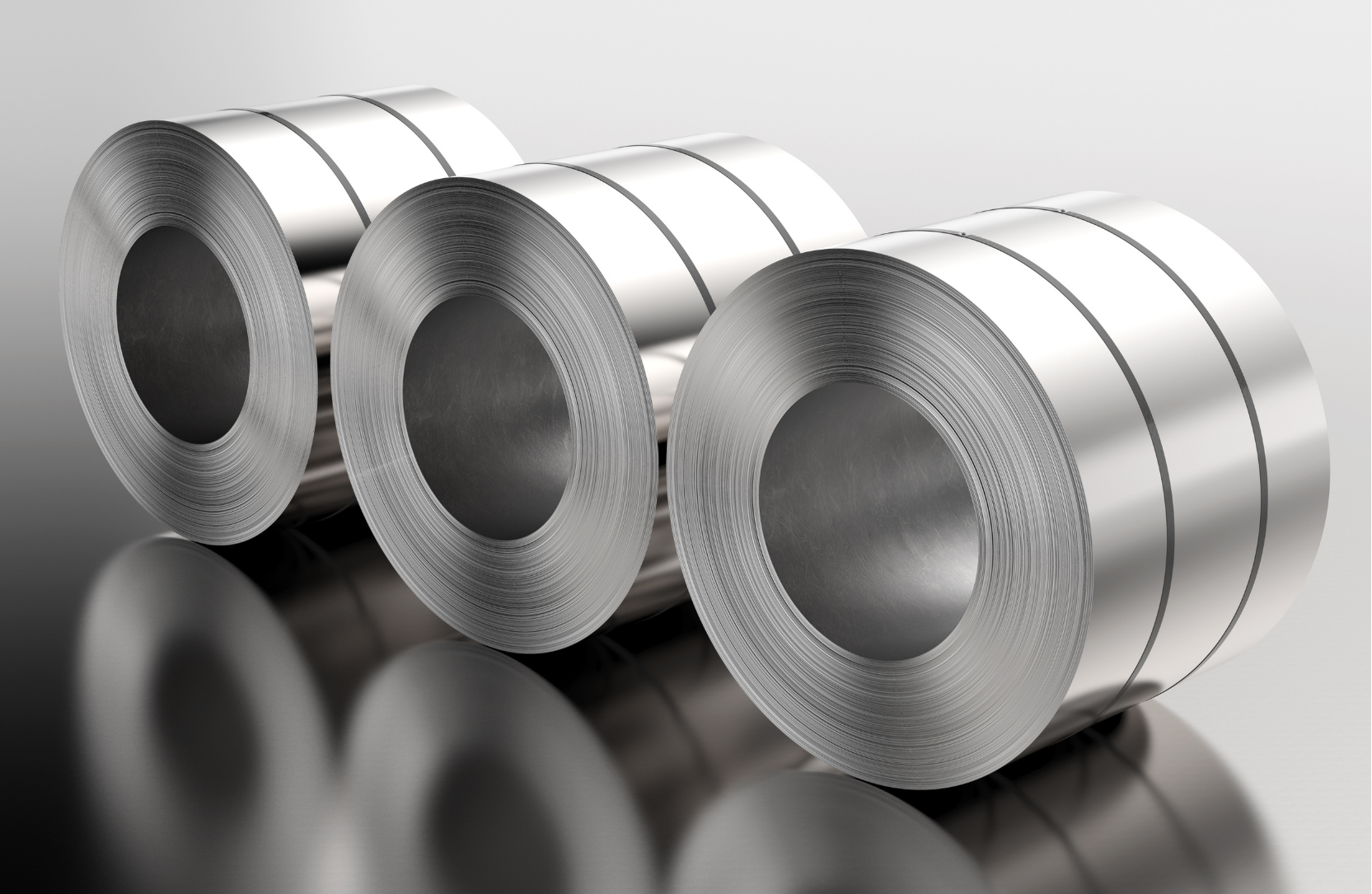 Three rolls of shiny, coiled metal stacked on a reflective surface.