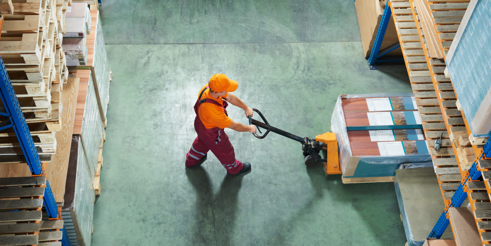 A man is pushing a pallet truck in a warehouse.