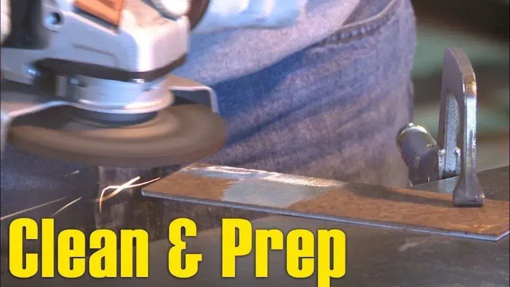 A person is using a grinder to clean and prep a piece of metal