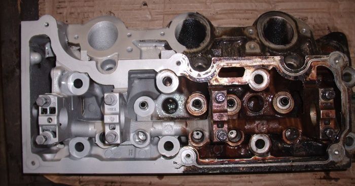Silver and oiled engine cylinder head with valves, ports and bolt holes.