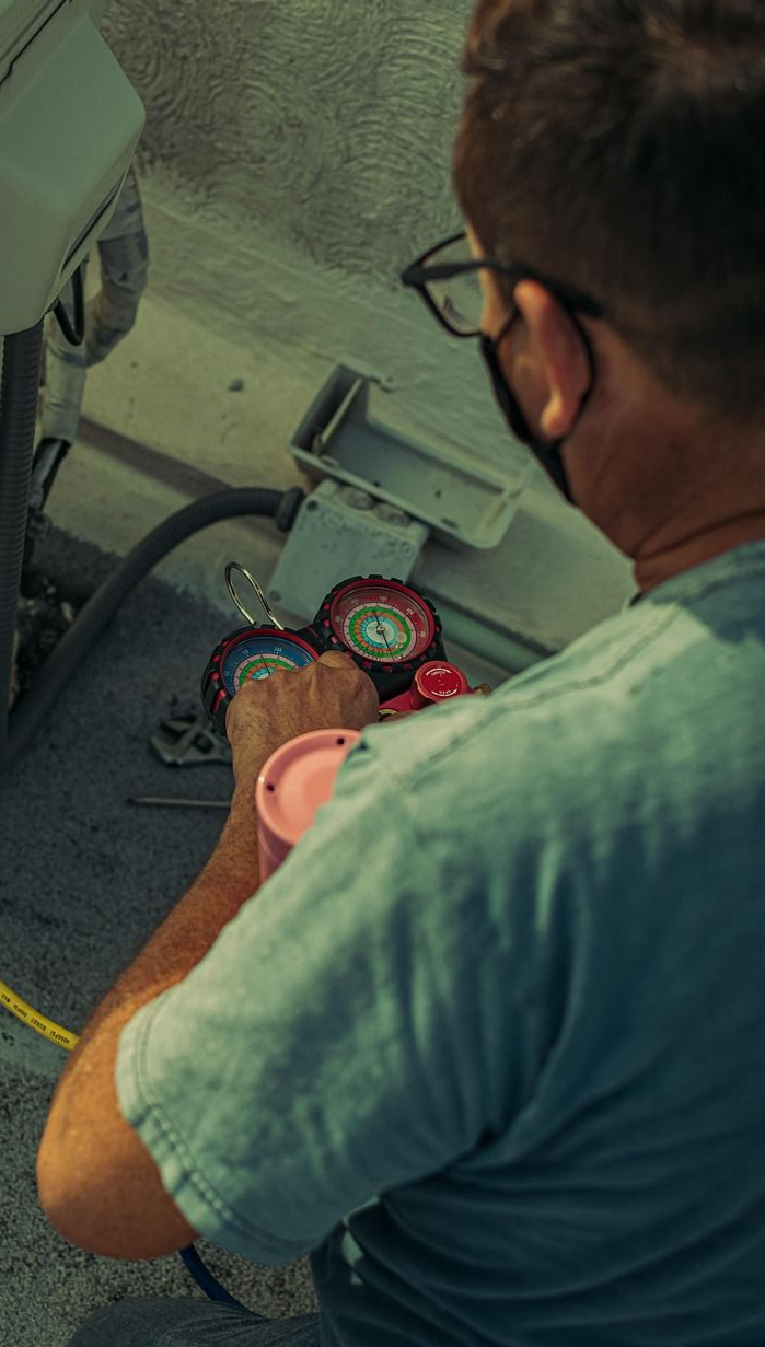 Man in mask using gauges on HVAC equipment.