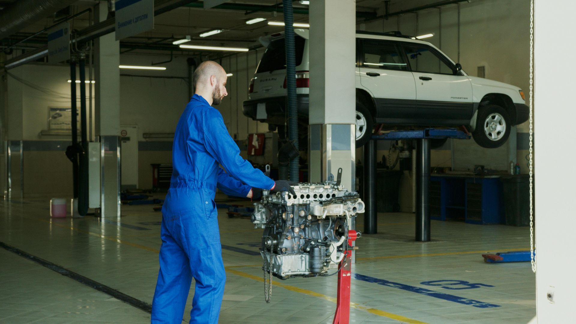 A mechanic is working on a car engine in a garage.