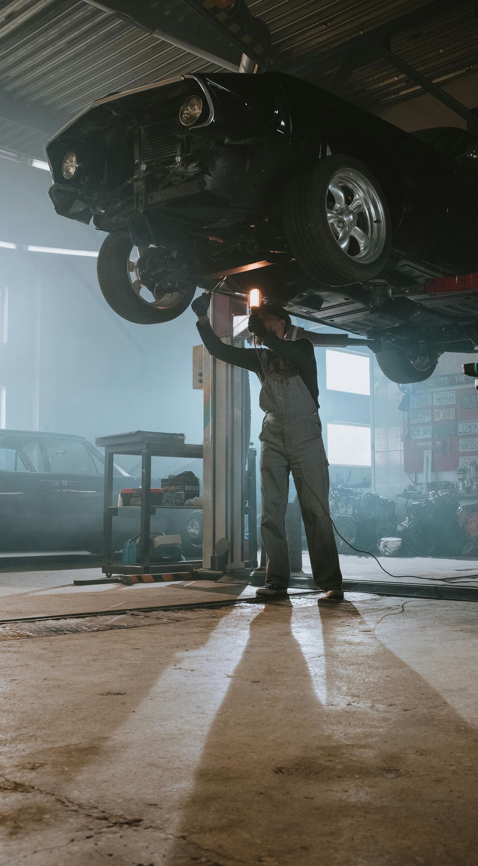 A man is working under a car in a garage.