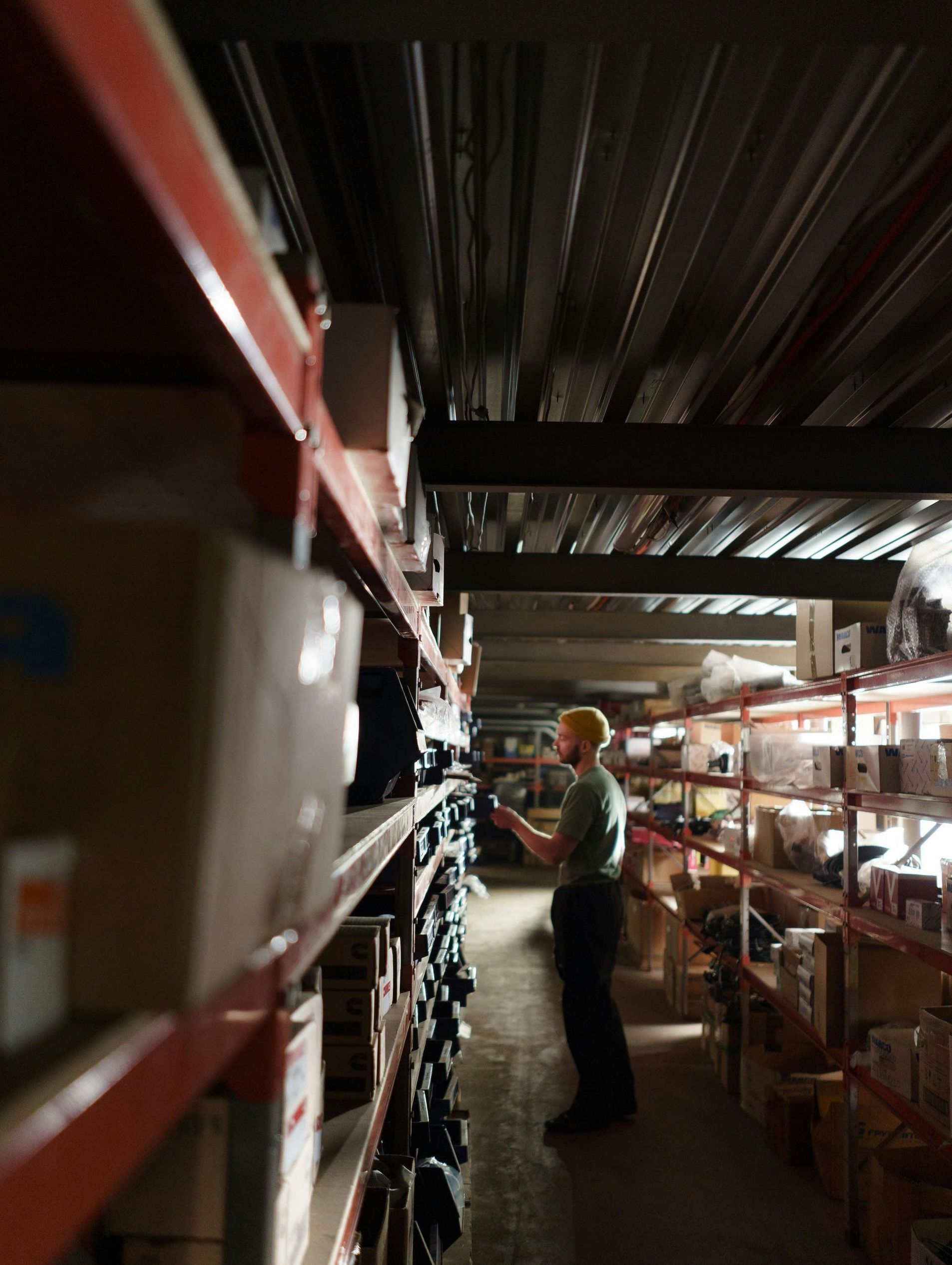 A man is standing in a warehouse looking at a tablet.