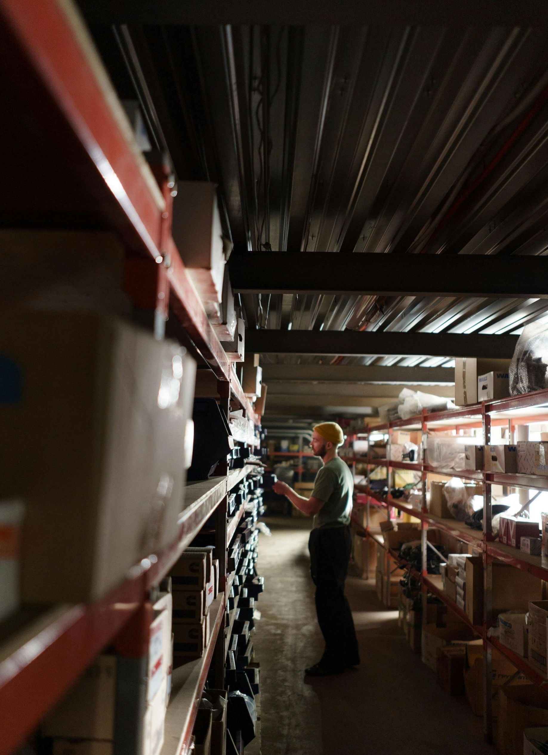 A man is standing in a warehouse looking at a tablet.
