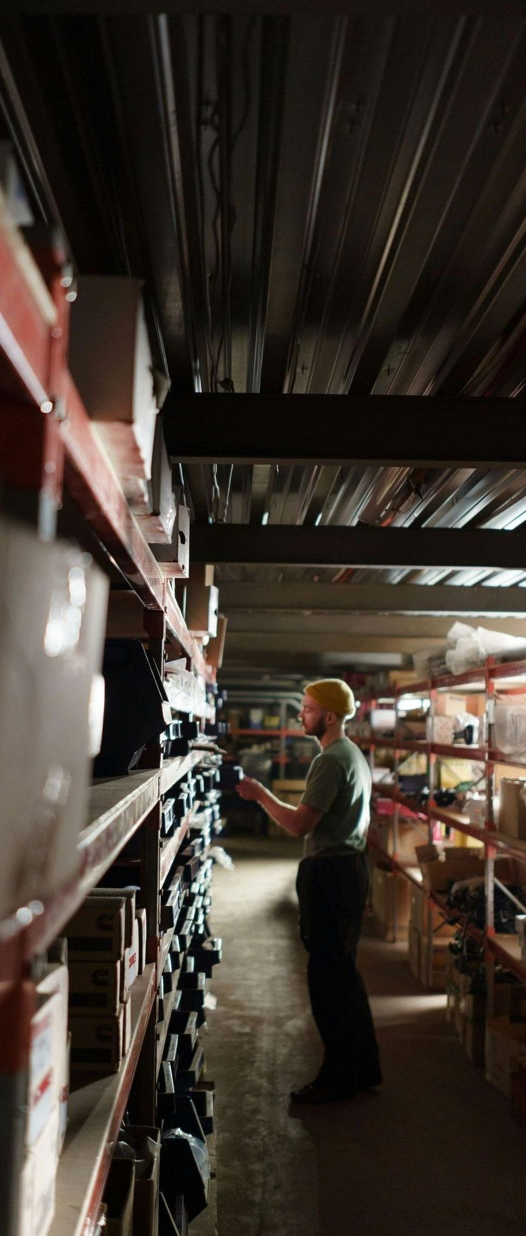 A man is standing in a warehouse looking at shelves.