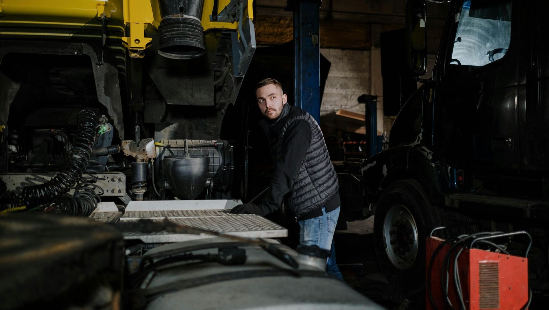 A man is working on a truck in a garage.