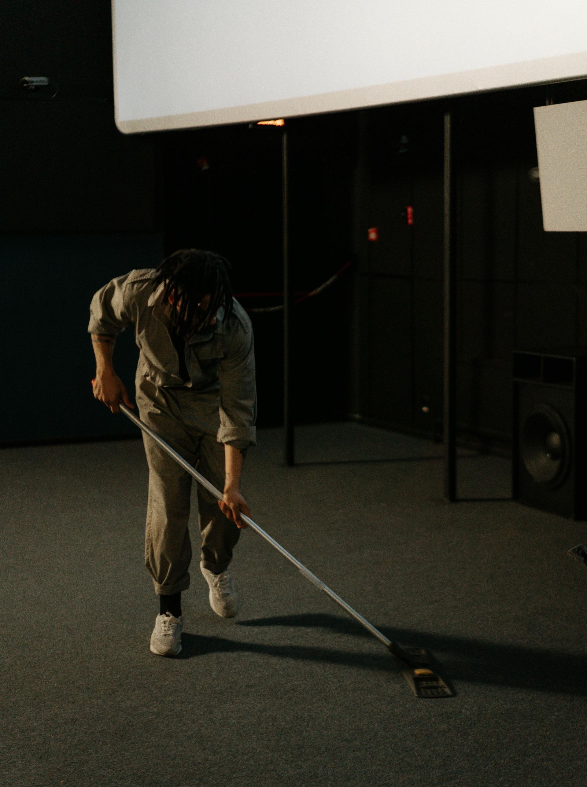 A man is mopping the floor in a dark room