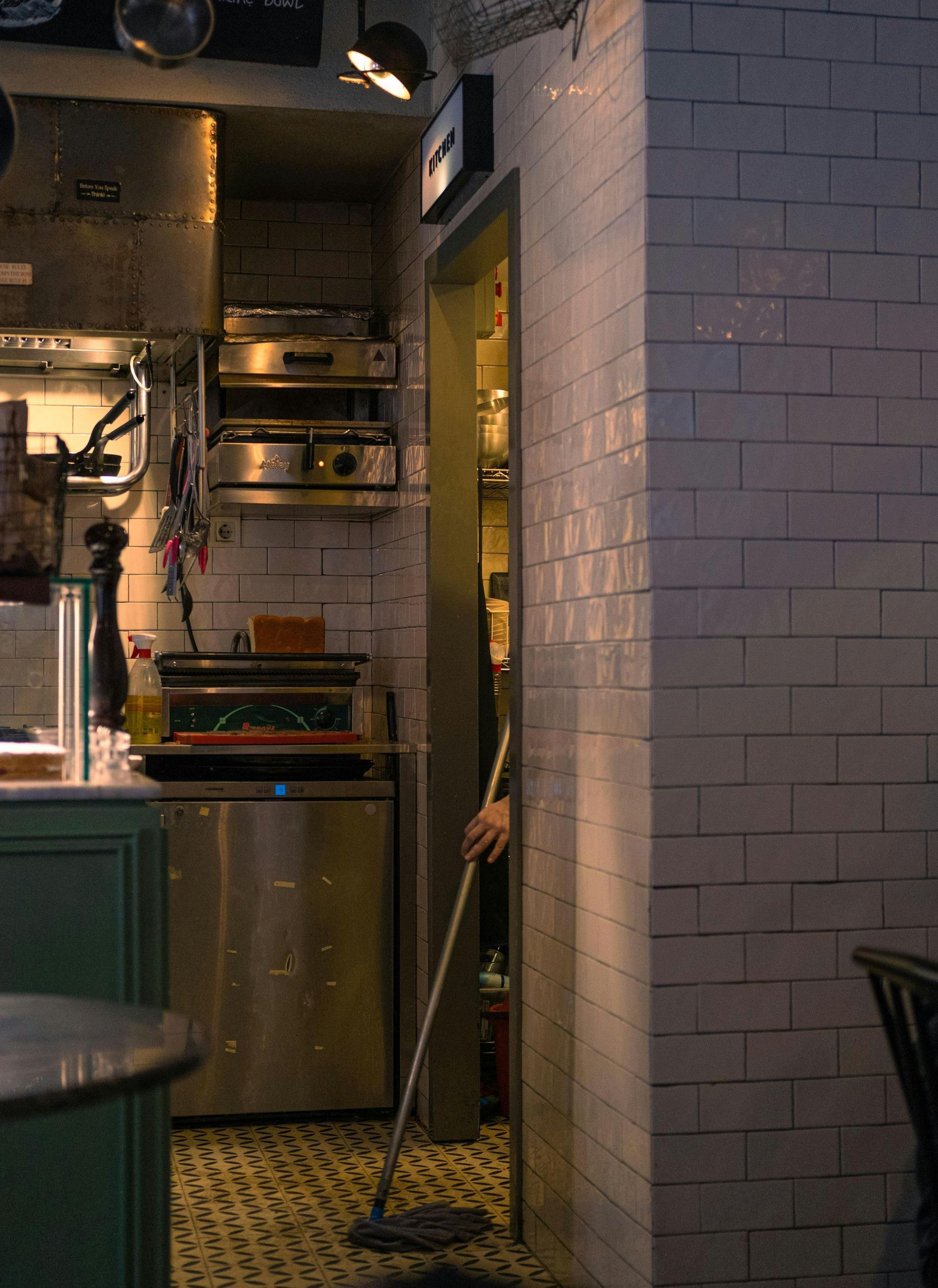 A person is holding a mop in a kitchen