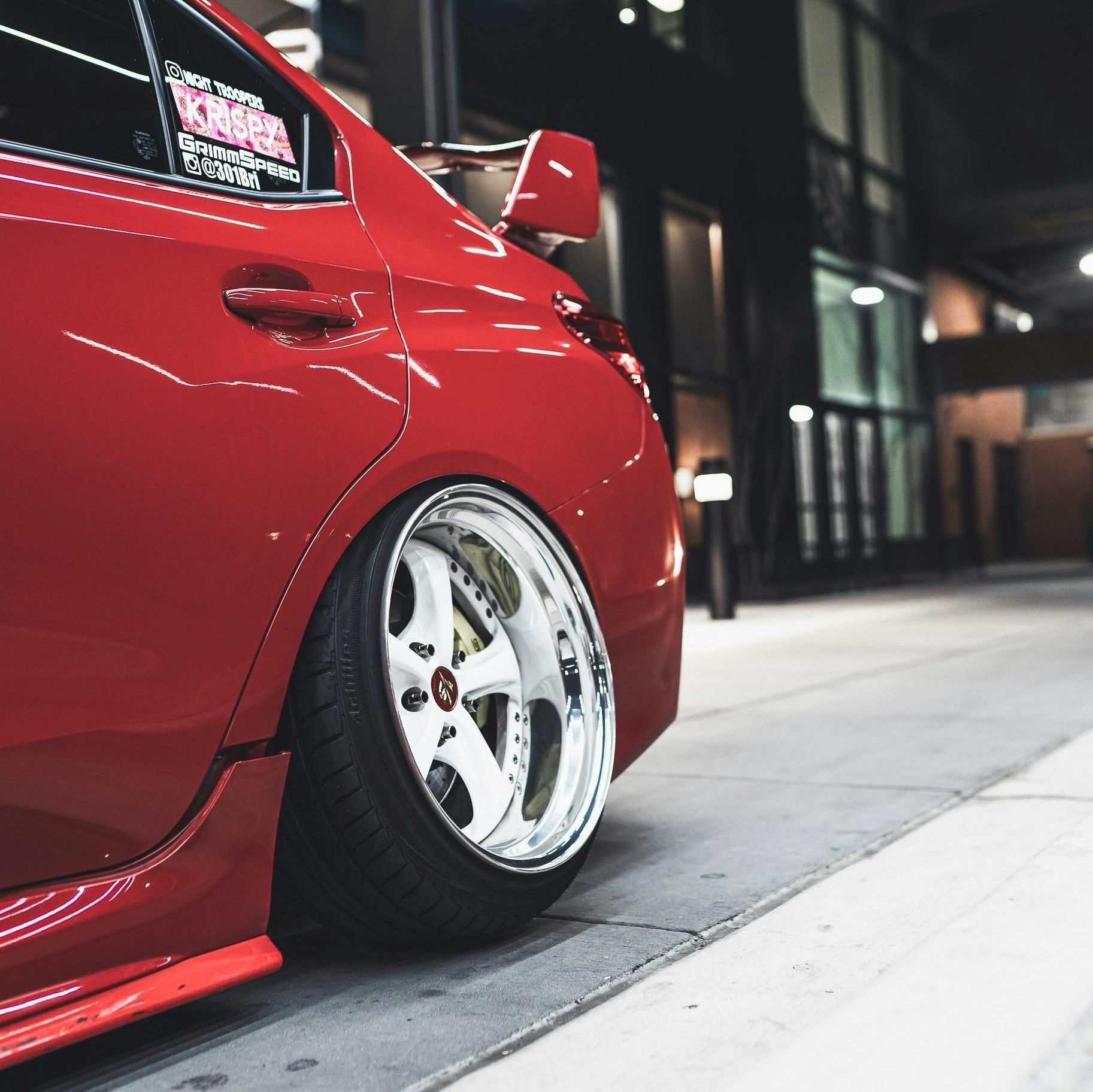 A red car is parked in a mechanic's shop