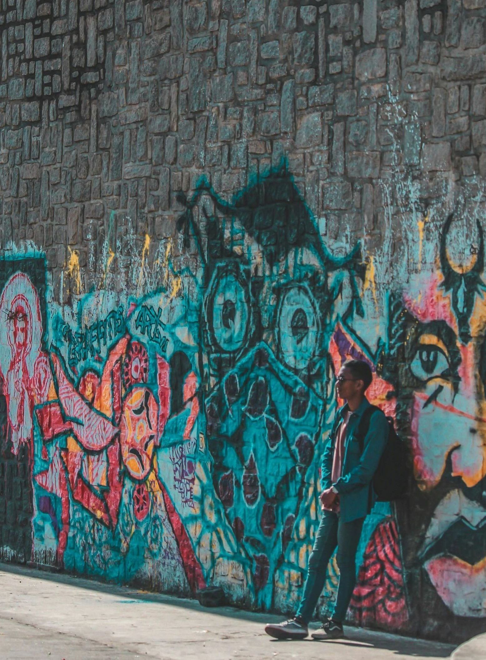 A man is walking past a wall with graffiti on it.