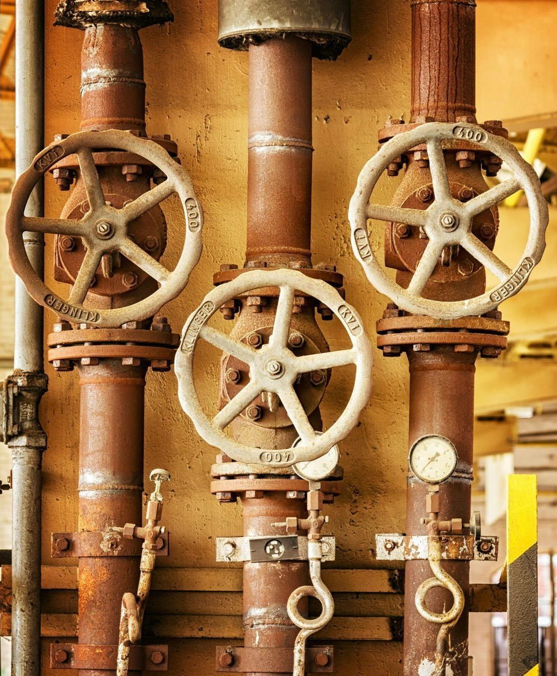 A row of rusty pipes with valves and a gauge on them