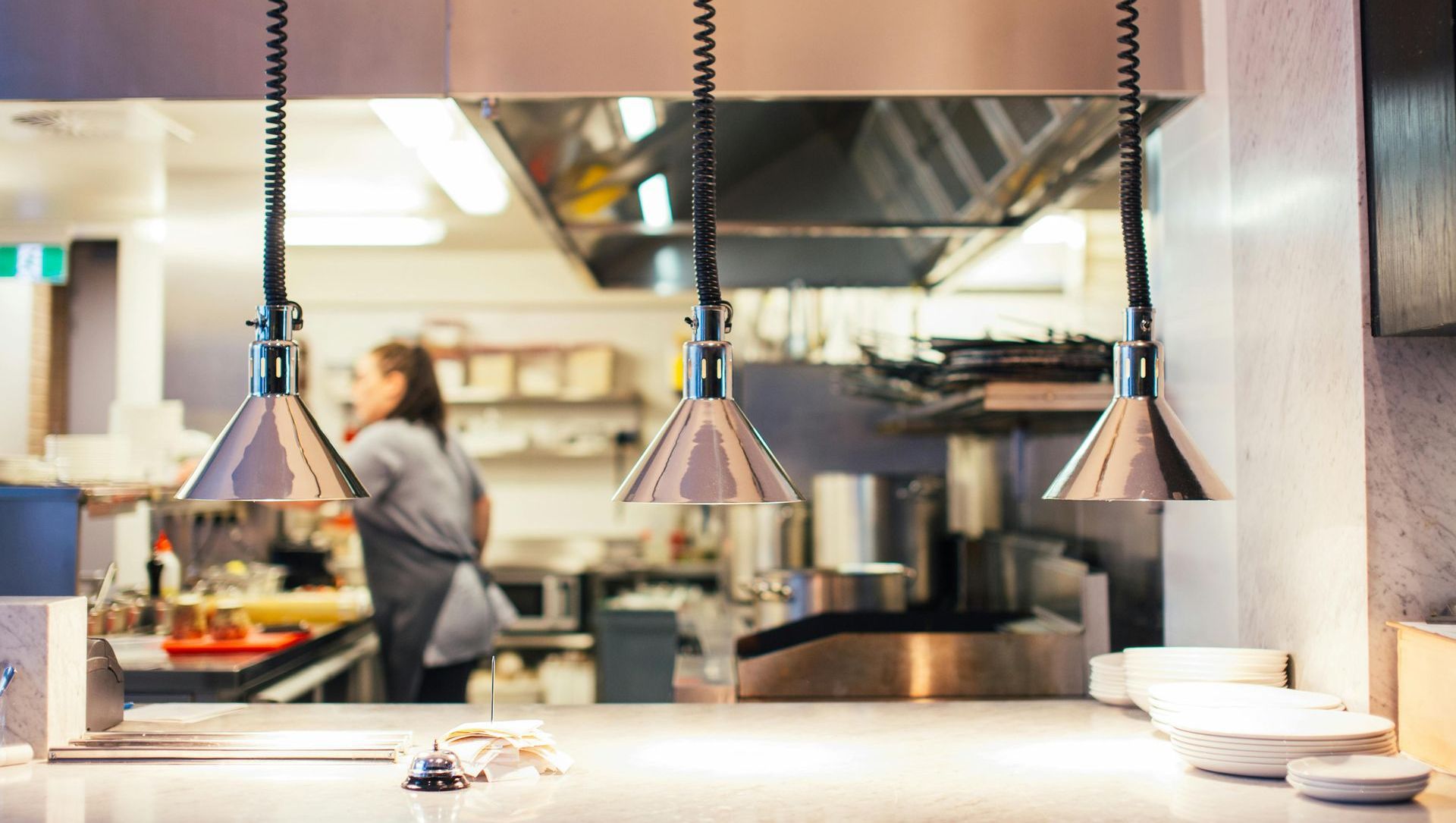 A blurry picture of a kitchen with a woman standing in the background.