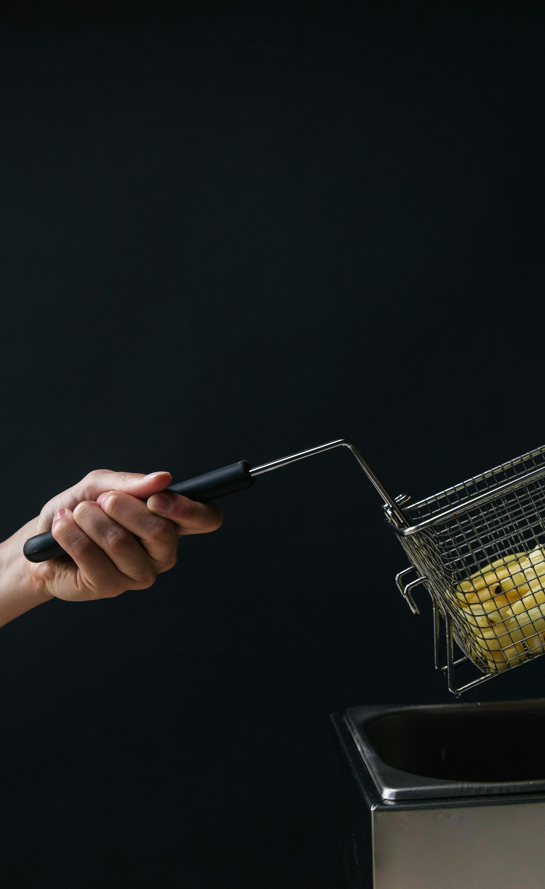 A person is pouring corn into a fryer.