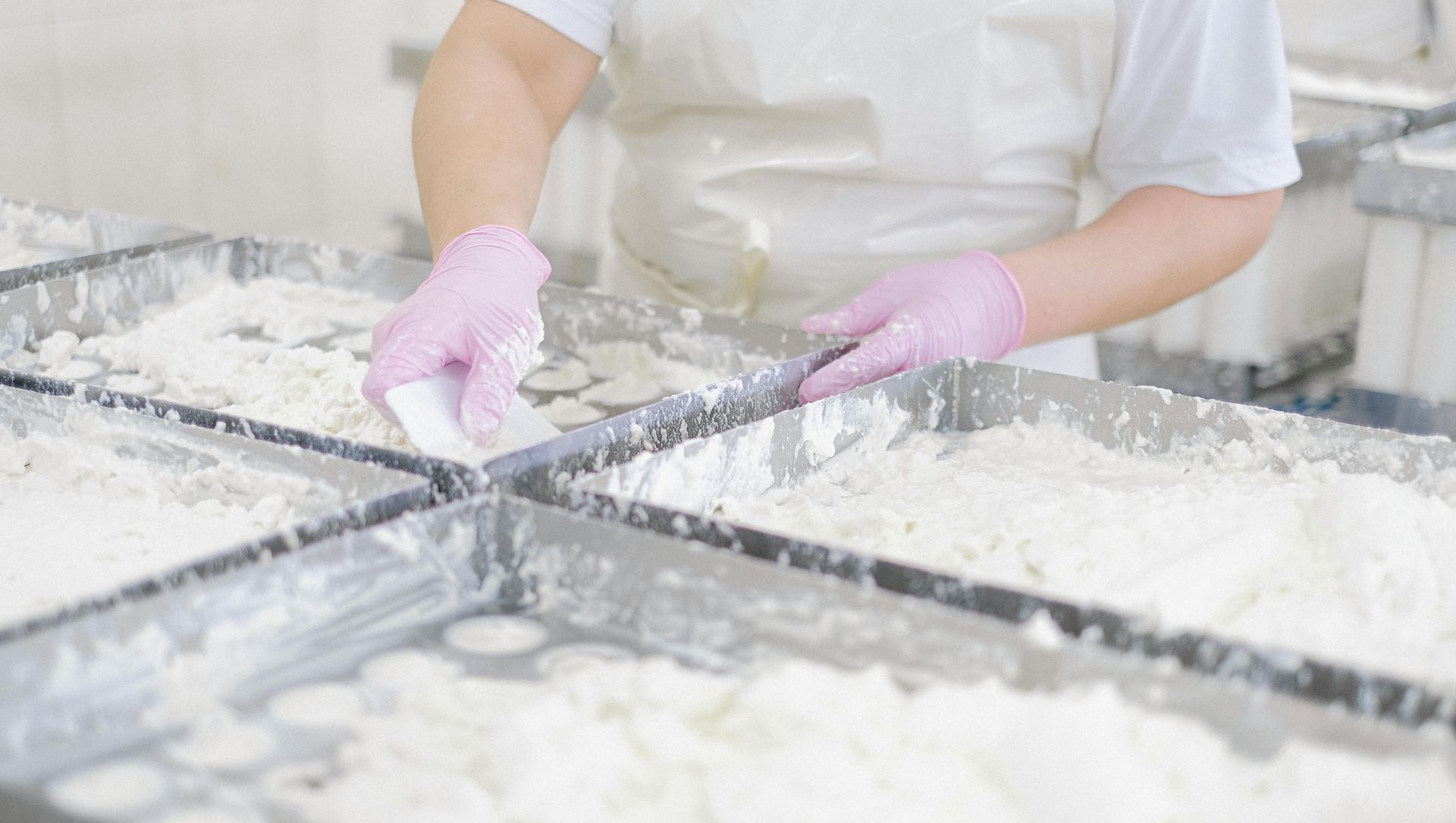 A person wearing pink gloves is working in a kitchen.