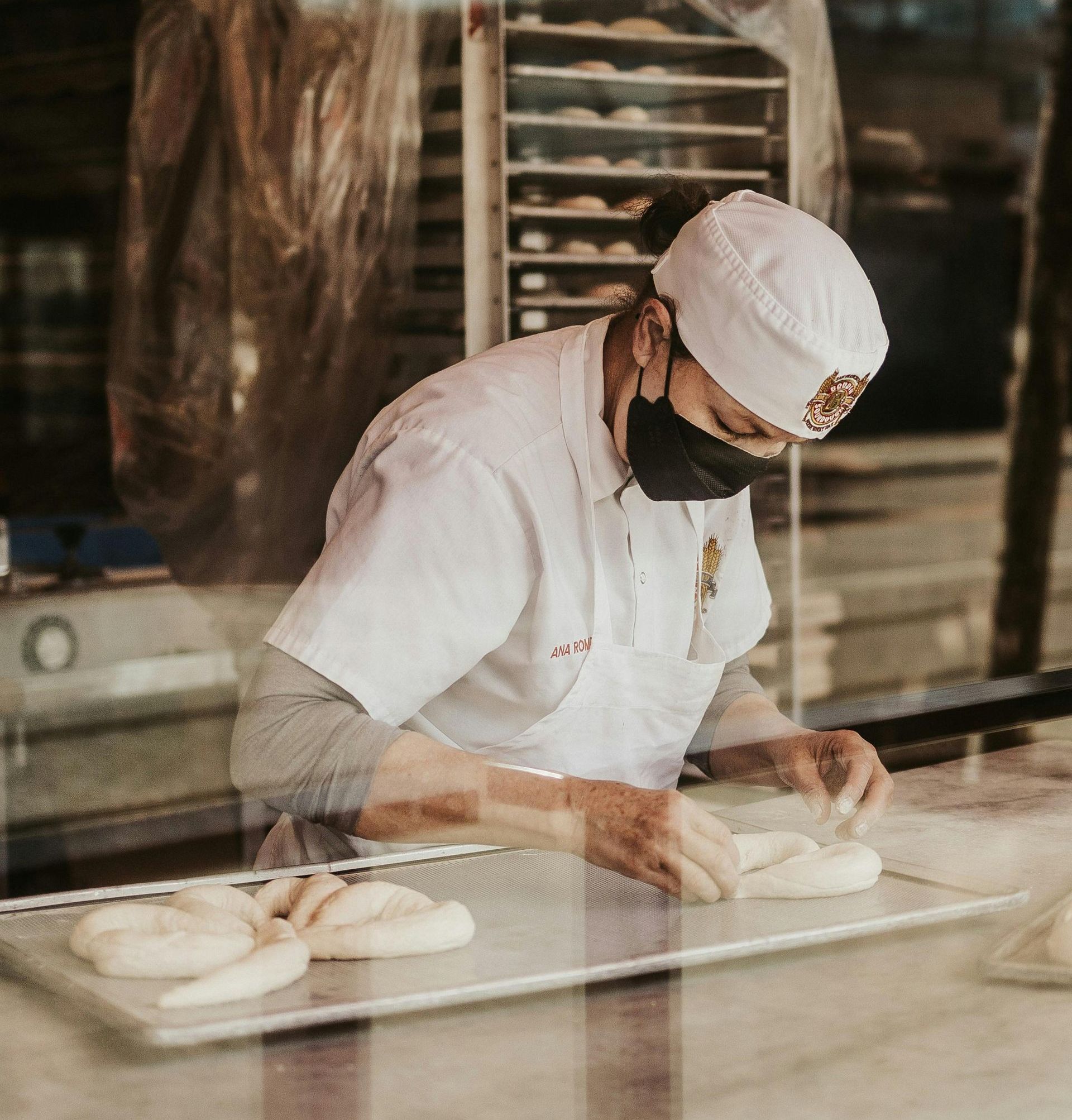 A man wearing a mask is working in a bakery.