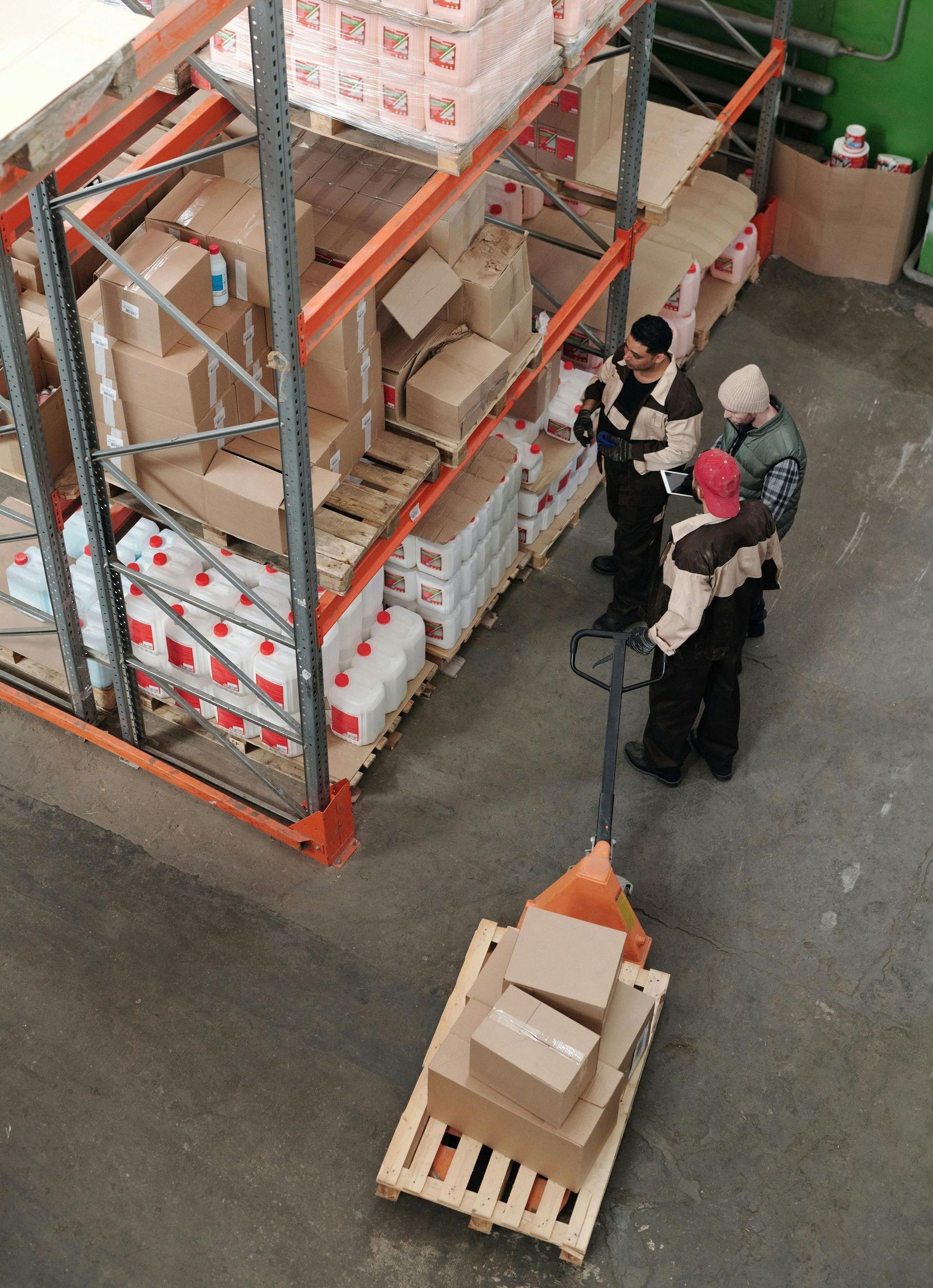 A group of people are standing around a pallet of boxes in a warehouse.