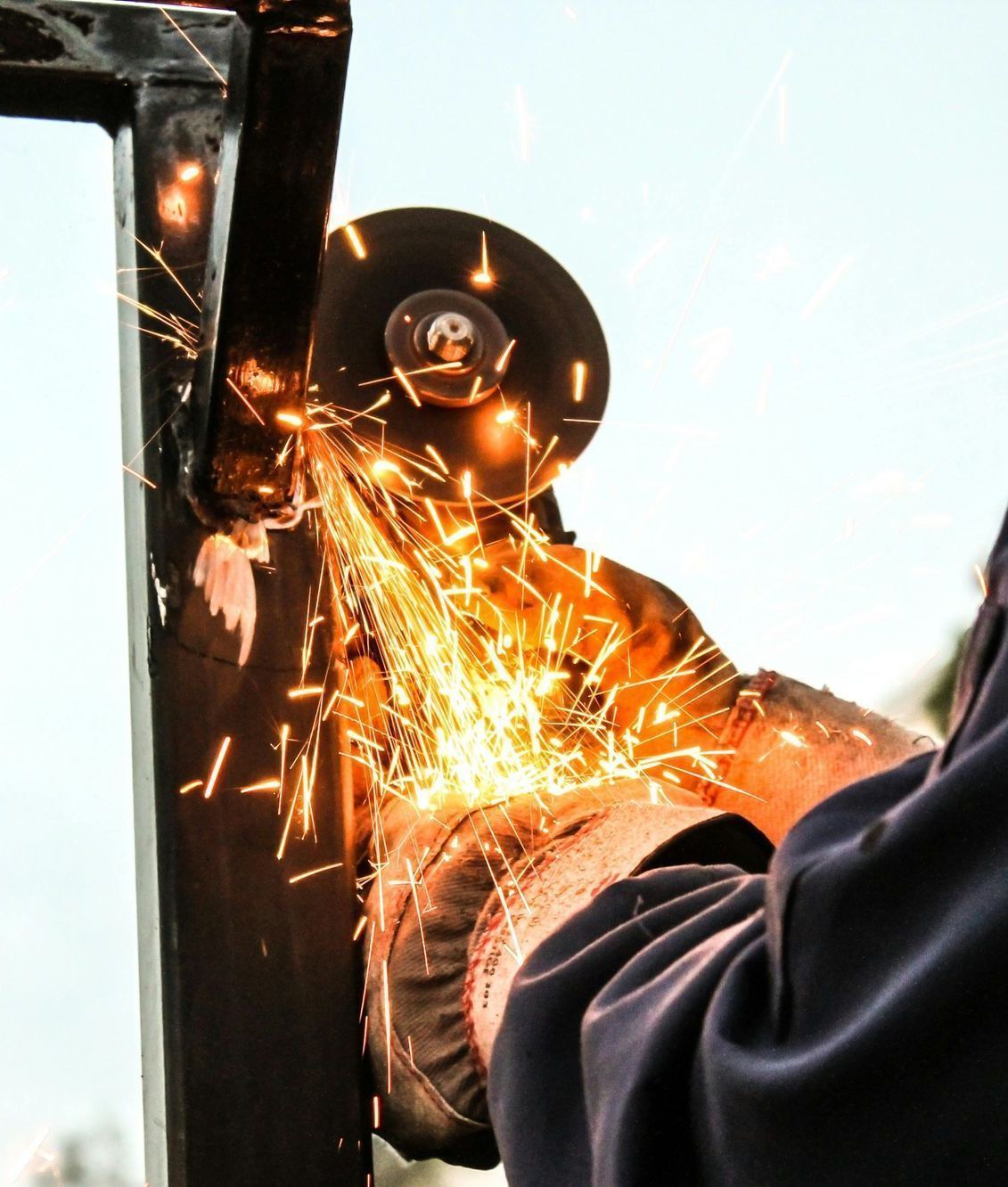 A person is using a grinder to cut a piece of metal