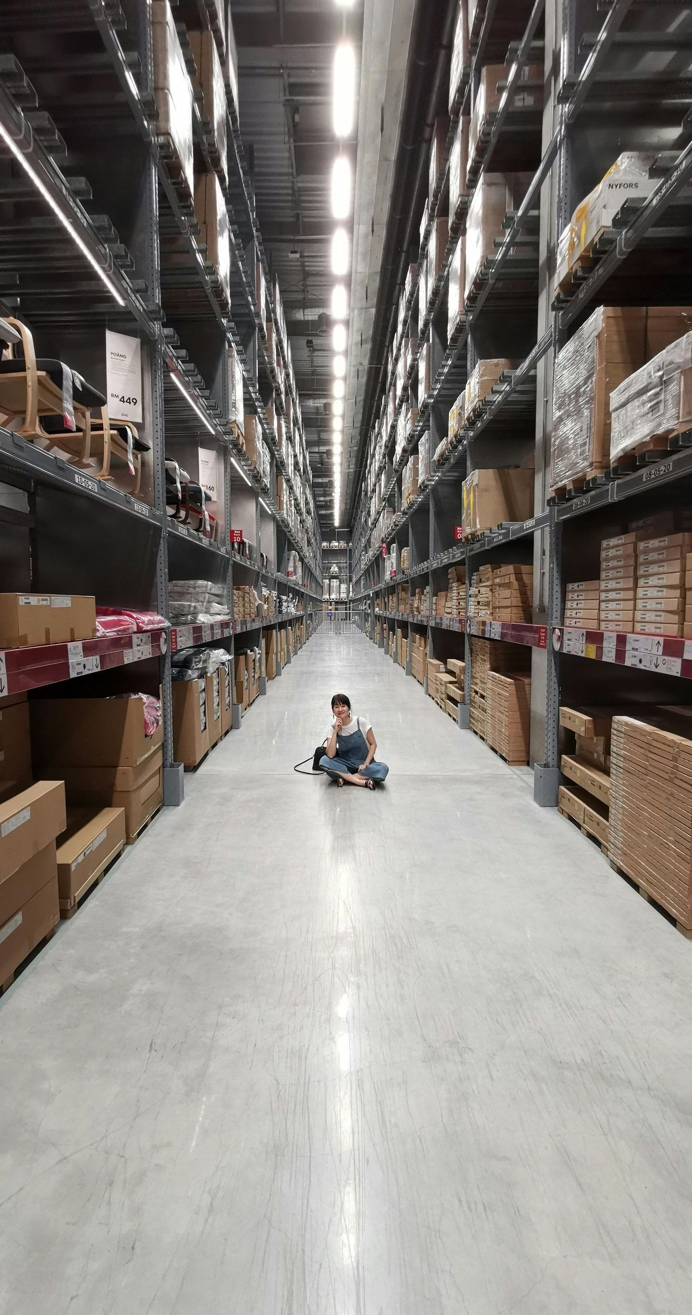 A little boy is sitting on the floor of a warehouse.