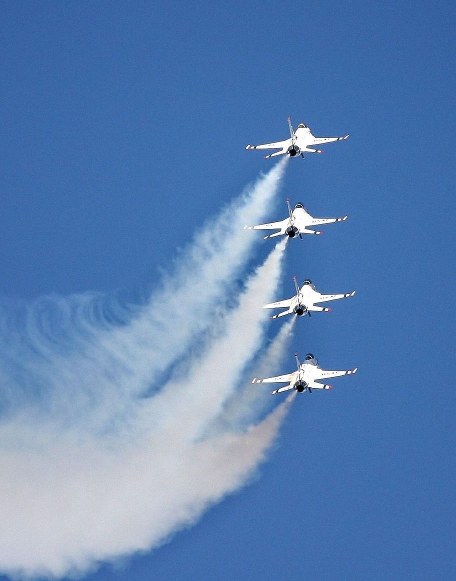 Four fighter jets are flying in formation in a blue sky