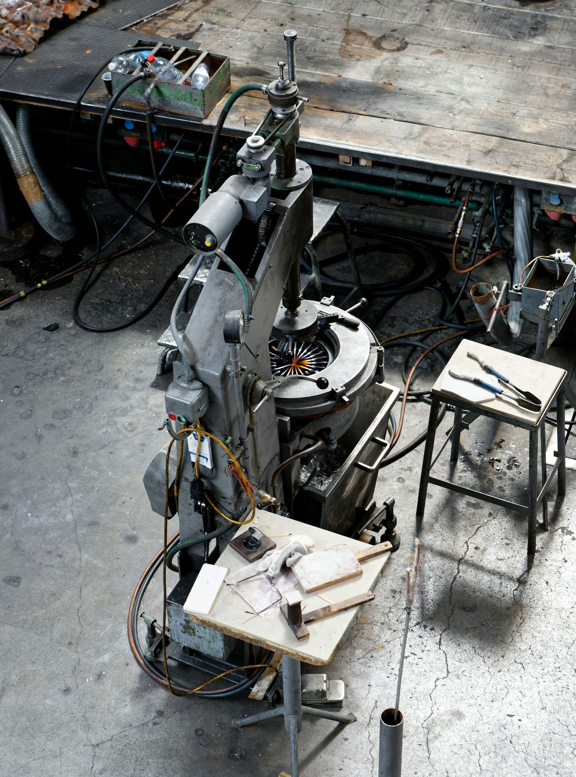 An overhead shot of a metalworking machine with a small work table holding tools. The setting appears to be a workshop.