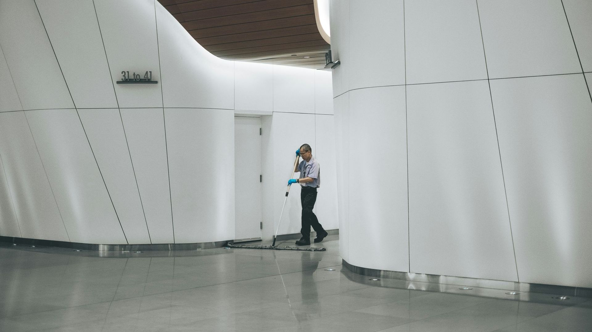 A man is cleaning the floor of a building with a mop.