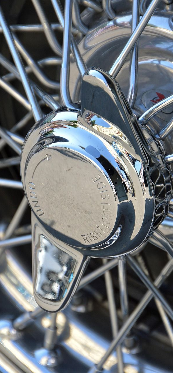 Shiny chrome hubcap of a wire wheel. Reflections and spokes are visible.