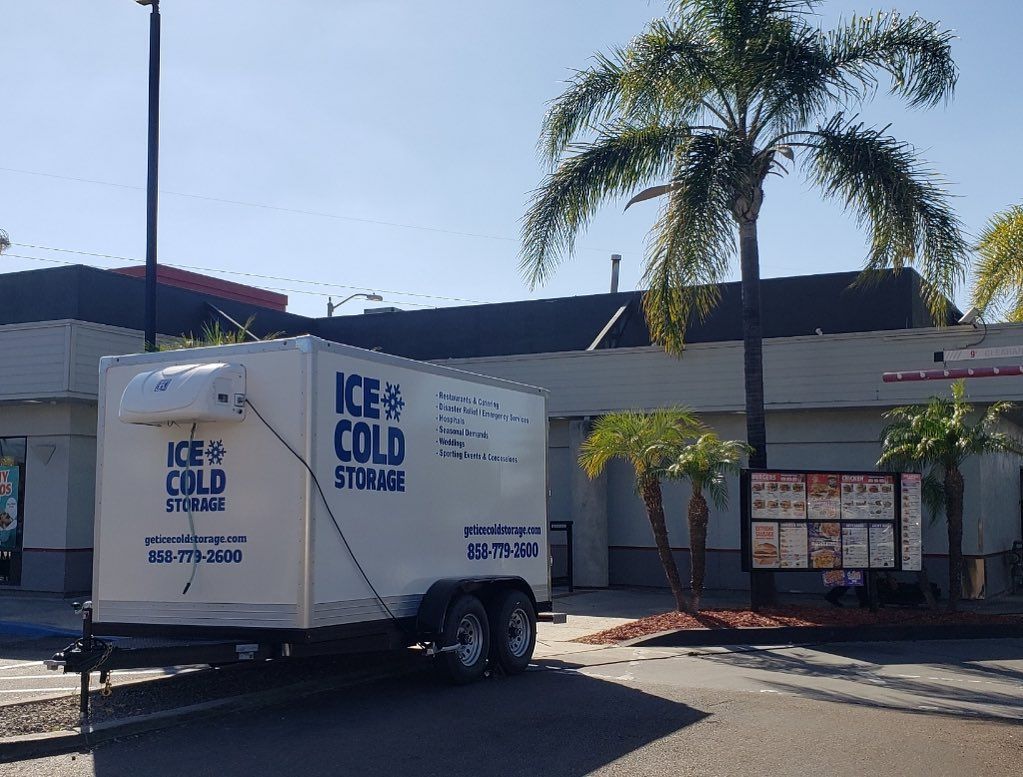 An ice cold trailer is parked in front of a building