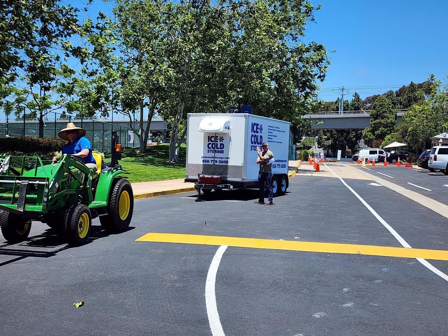 A man is driving a john deere tractor in a parking lot