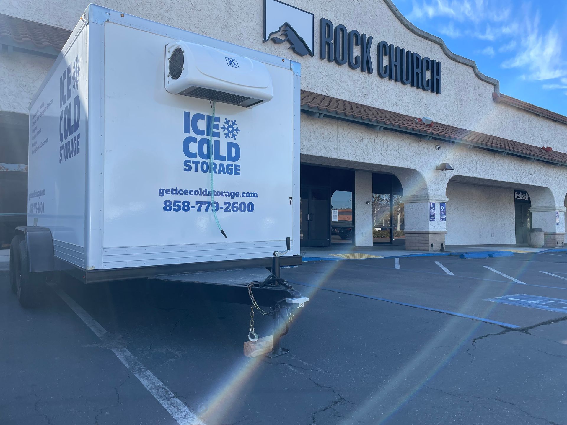 A trailer for ice cold storage is parked in front of a building.