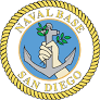 Official seal of Naval Base San Diego, featuring a hand gripping an anchor against a blue circular background.