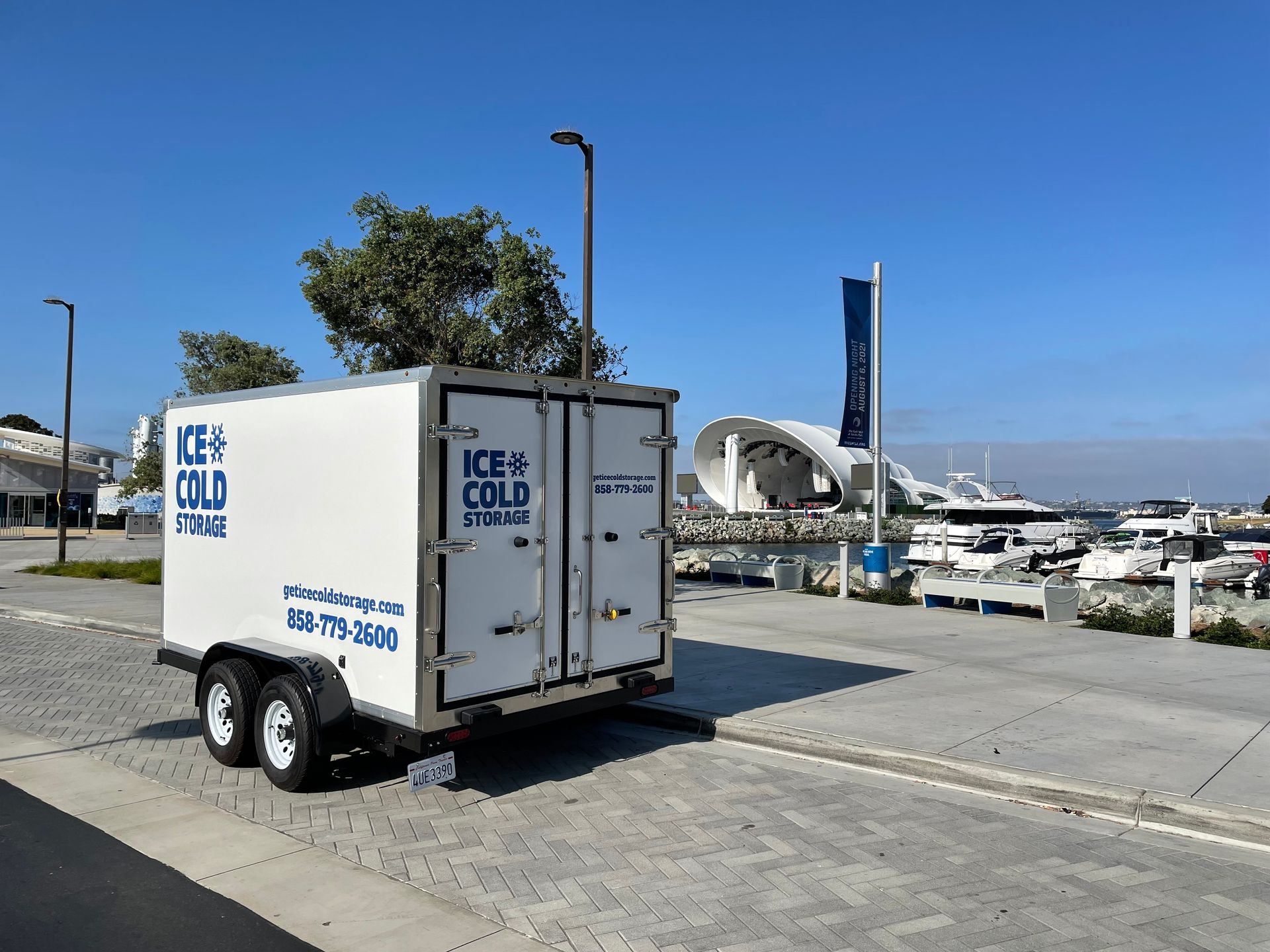 A trailer that says ice cold is parked on the side of the road.