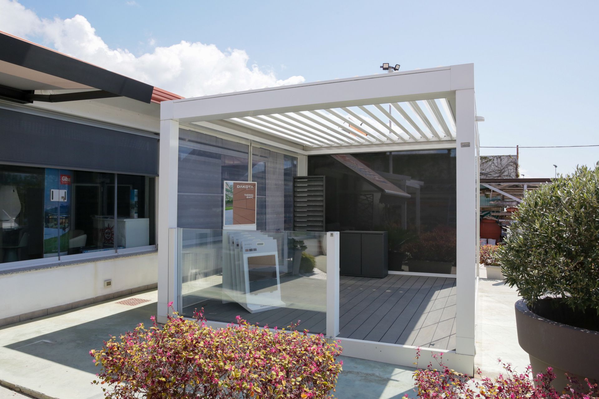 Un pergolato bianco è situato in cima a un patio di fronte a un edificio.
