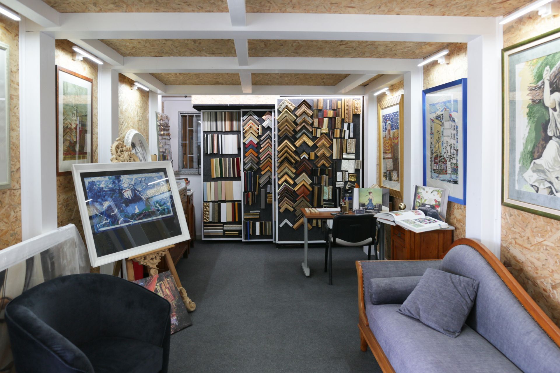 Un soggiorno con un divano, una sedia, una scrivania e quadri alle pareti.