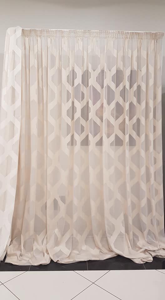 Una tenda bianca con un motivo è appesa a una parete.