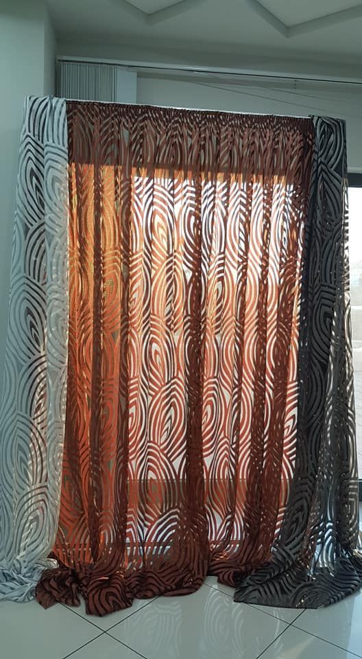 Un mucchio di tende sono appese a una finestra in una stanza.