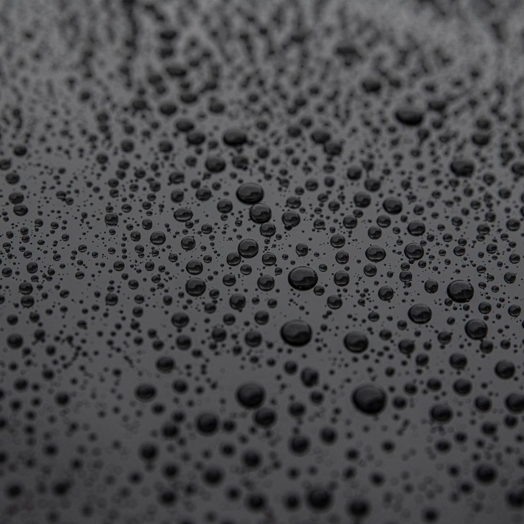 A close up of water drops on a black surface.