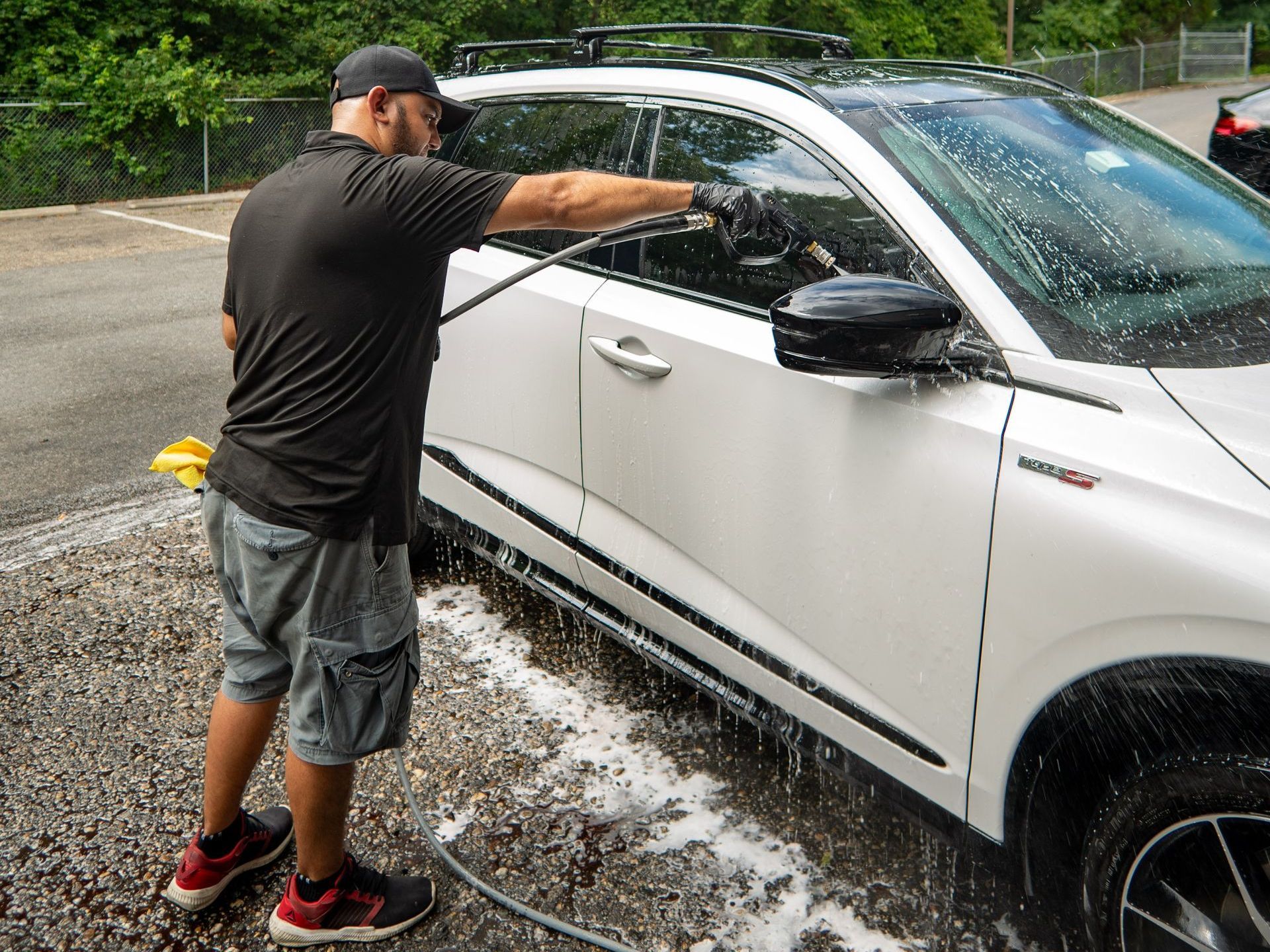 A man is washing a white car with a hose