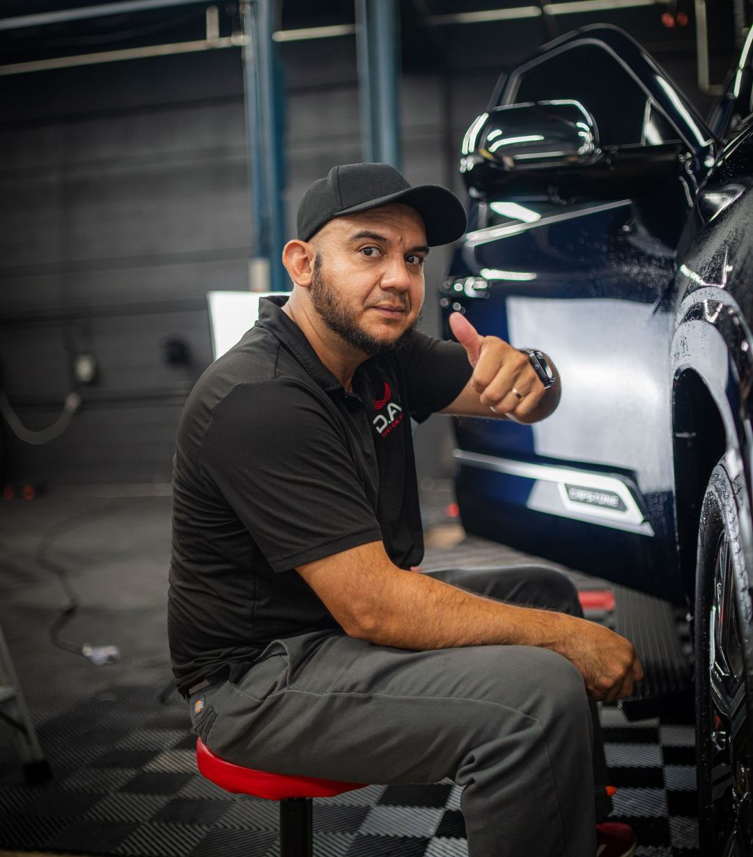 A man is polishing the hood of a black truck.