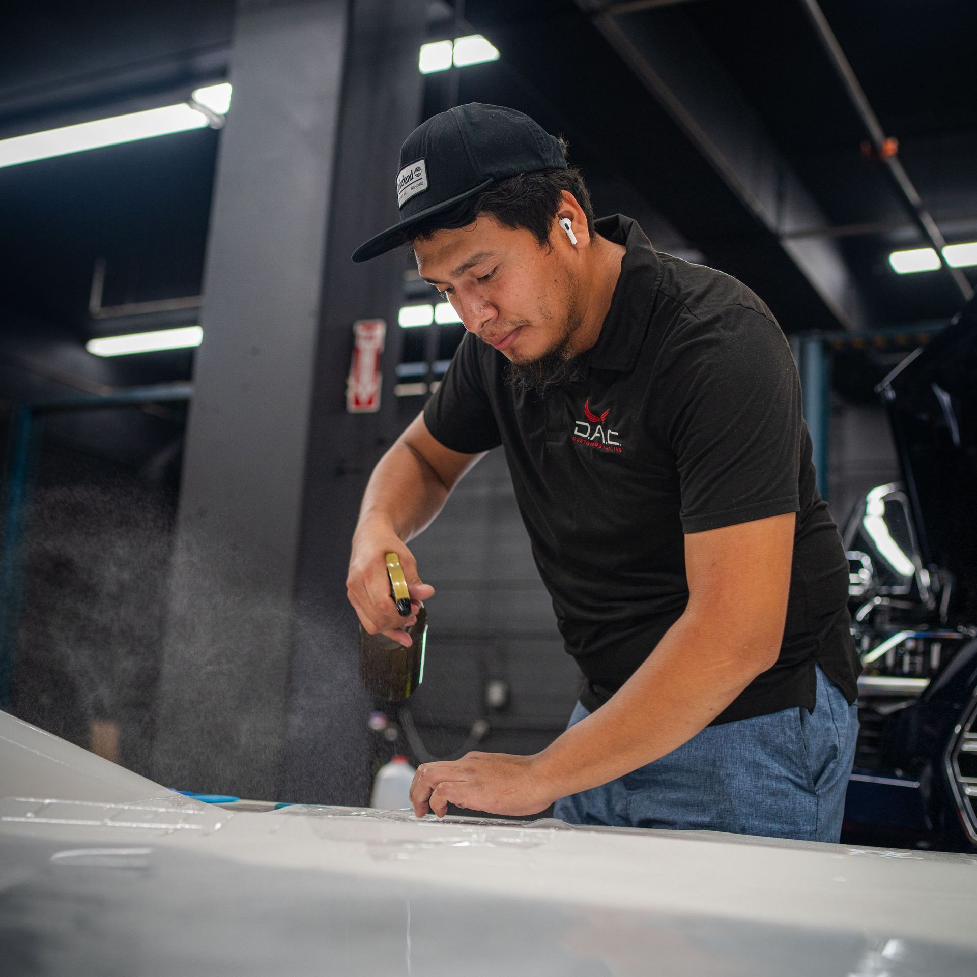 A man is working on the hood of a car in a garage.